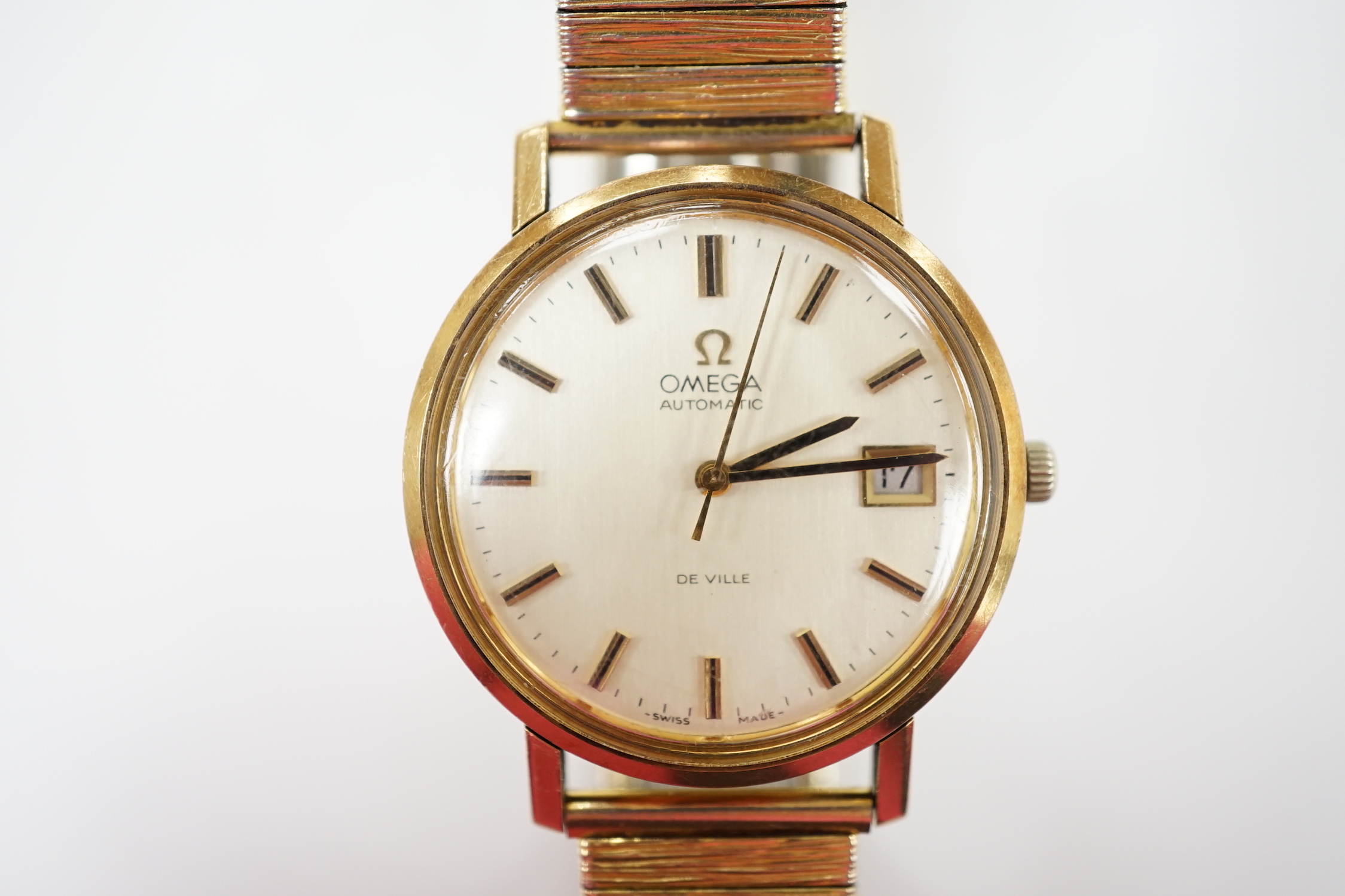 A gentleman's yellow metal Omega De Ville automatic wrist watch, with baton numerals and date aperture, case diameter 34mm, on an associated gold plated bracelet.